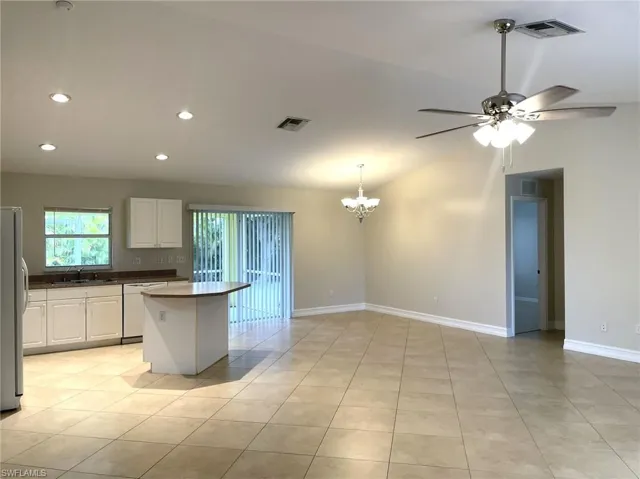 Kitchen with white cabinetry, ceiling fan with notable chandelier, sink, white dishwasher, and light tile patterned floors