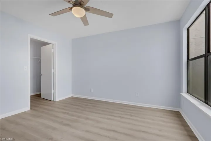 Unfurnished bedroom featuring a spacious closet, light wood-style flooring, and ceiling fan