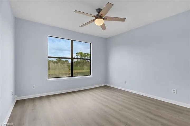 Empty room featuring light wood-style floors, a textured ceiling, and a ceiling fan