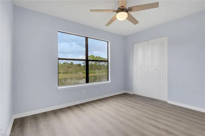 Unfurnished bedroom with light wood-type flooring, a closet, ceiling fan, a water view, and a textured ceiling