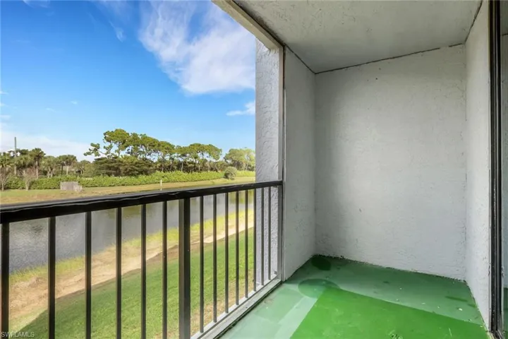 Balcony featuring a sunroom, view of scattered trees, and a water view