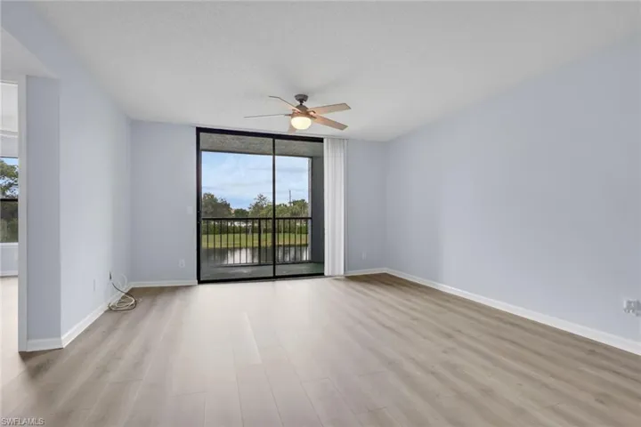 Empty room with floor to ceiling windows, a textured ceiling, light wood-style flooring, and a ceiling fan