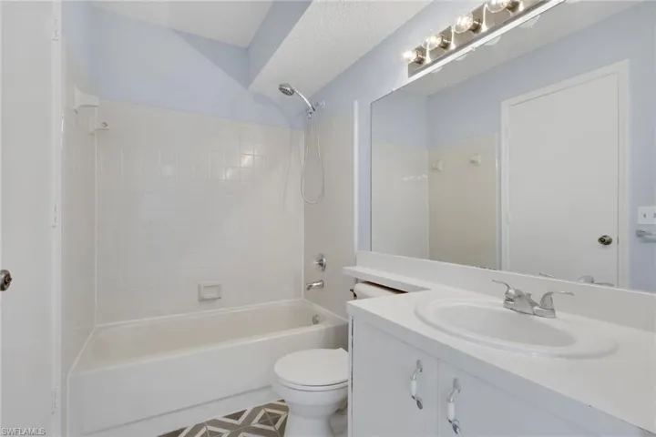 Full bath featuring vanity, tub / shower combination, and a textured ceiling