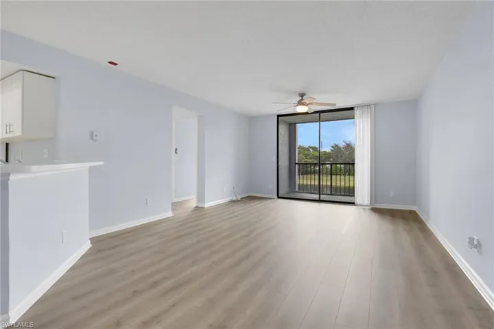 Unfurnished living room featuring light wood-style floors, a wall of windows, ceiling fan, and a textured ceiling