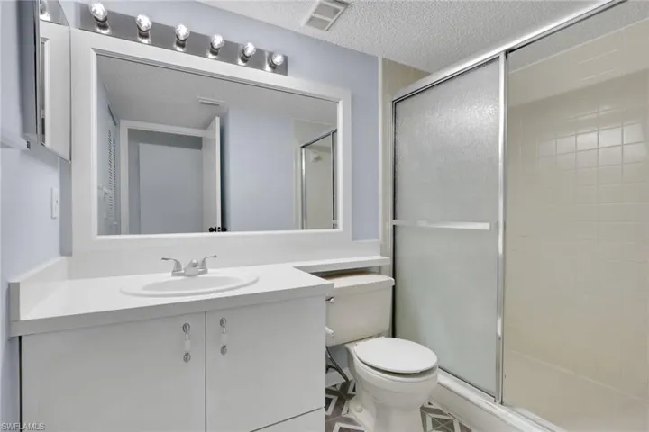 Bathroom featuring vanity, a textured ceiling, and a shower stall