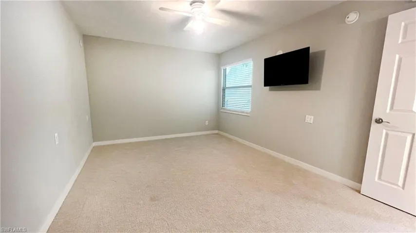 Unfurnished bedroom featuring light carpet, ceiling fan, baseboards, and a smoke detector