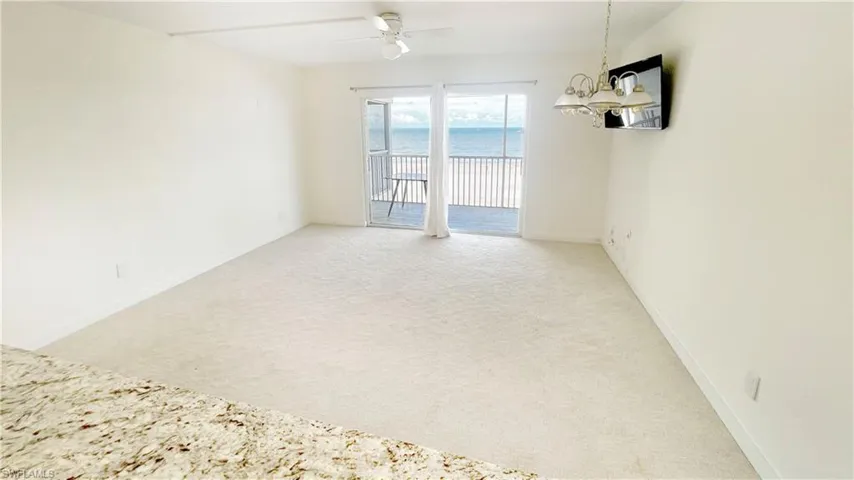 Living room with light colored carpet, a ceiling fan, baseboards, and a chandelier