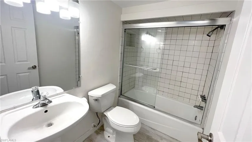 Bathroom featuring enclosed tub / shower combo, sink and toilet