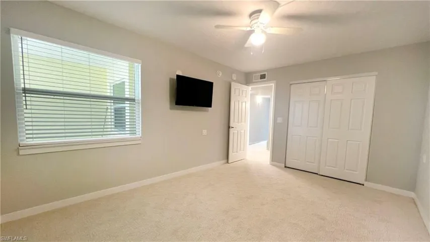 Unfurnished bedroom featuring light carpet, ceiling fan, baseboards, and a smoke detector