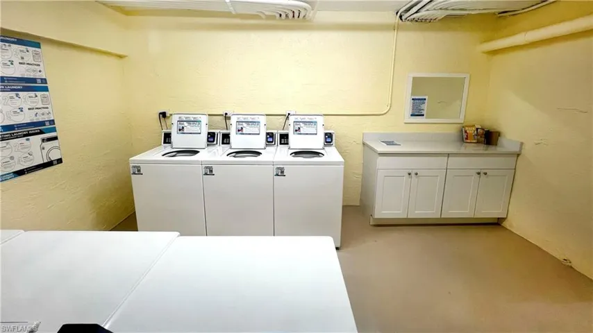 Community laundry room with a textured wall and separate washers and dryers