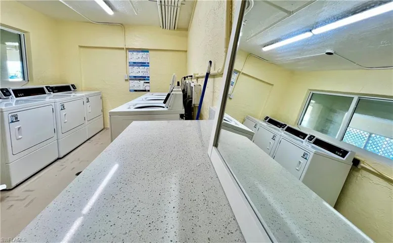 Community laundry room featuring a textured wall and washing machine and dryer