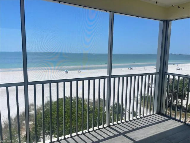 Unfurnished sunroom featuring view of water and beach