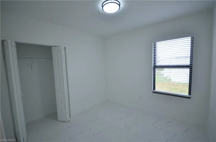 Unfurnished bedroom featuring a closet, marble finish floor, and baseboards