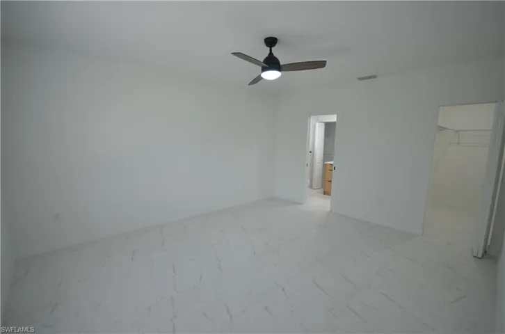 Unfurnished bedroom with visible vents, a walk in closet, ceiling fan, a closet, and marble finish floor