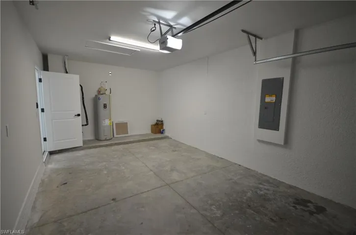 Garage with electric panel, a garage door opener, and electric water heater