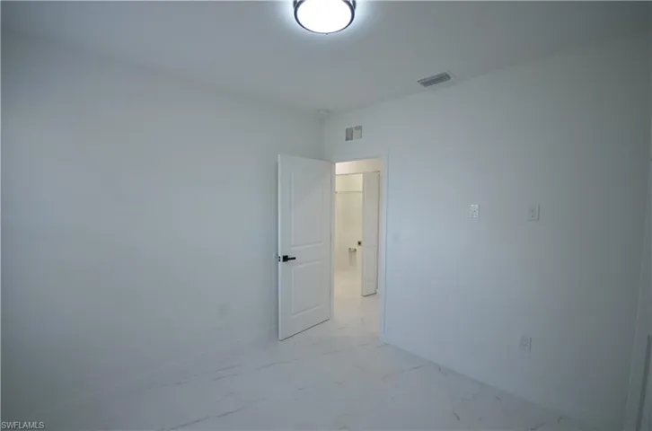 Empty room with visible vents, marble finish floor, and baseboards