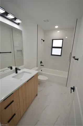 Full bath with visible vents, toilet, marble finish floor, shower / tub combination, and vanity