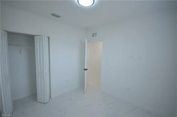 Unfurnished bedroom featuring a closet, visible vents, marble finish floor, and baseboards