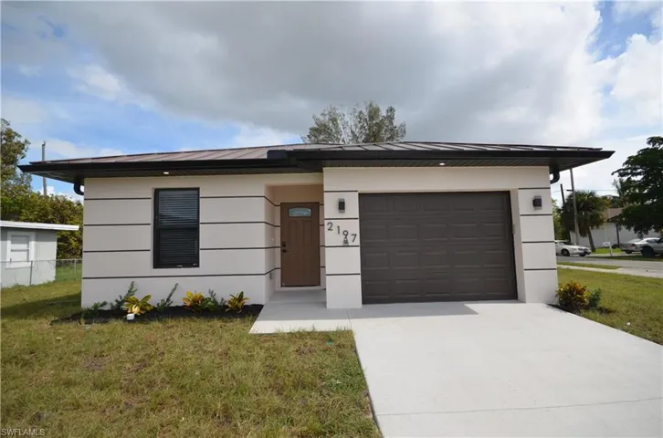 View of front facade with a front lawn, driveway, a standing seam roof, metal roof, and a garage