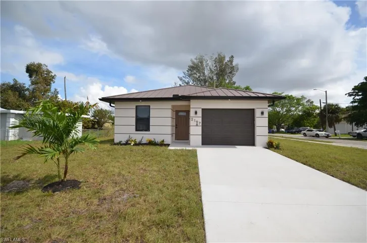 View of front of home featuring a front lawn, concrete driveway, metal roof, a garage, and a standing seam roof