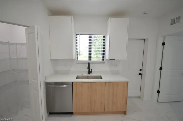 Kitchen featuring visible vents, dishwasher, marble finish floor, modern cabinets, and a sink