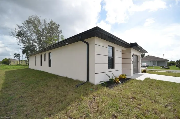 View of property exterior featuring stucco siding, driveway, an attached garage, and a yard