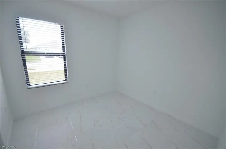 Spare room featuring marble finish floor and baseboards
