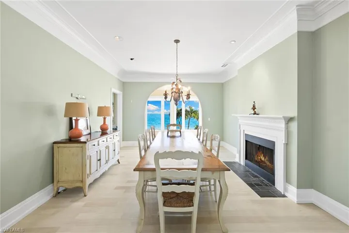 Dining space featuring light wood-type flooring, ornamental molding, a fireplace with flush hearth, a chandelier, and recessed lighting