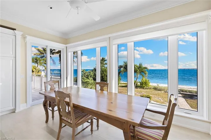 Dining area featuring view of water and beach, light wood finished floors, ceiling fan, and ornamental molding