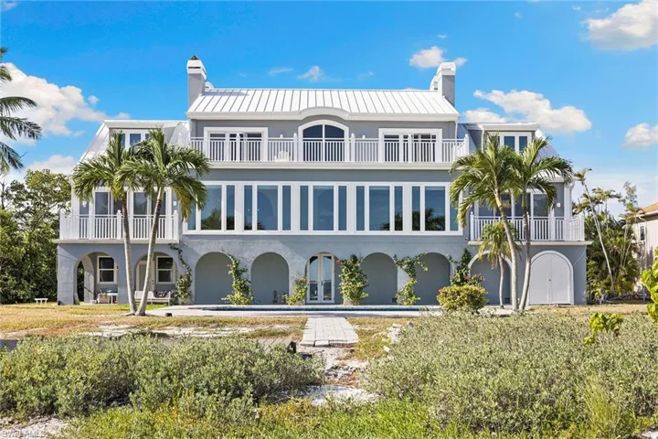 Back of house featuring stucco siding, french doors, a balcony, and a chimney