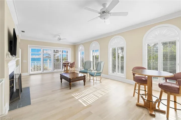 Living room featuring crown molding, light wood finished floors, ceiling fan, and a premium fireplace