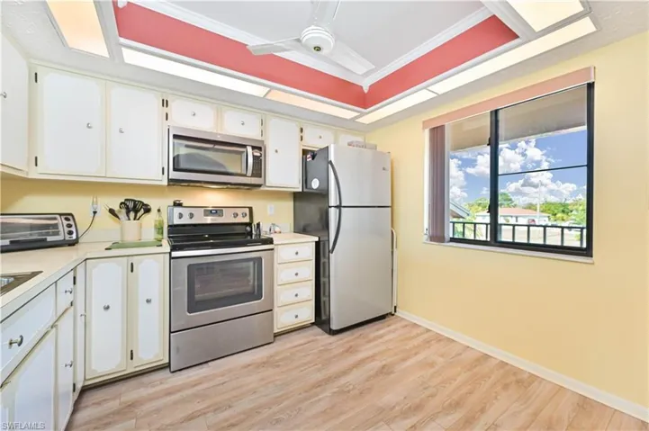 Kitchen featuring stainless steel appliances, light countertops, light wood-style floors, crown molding, and white cabinets