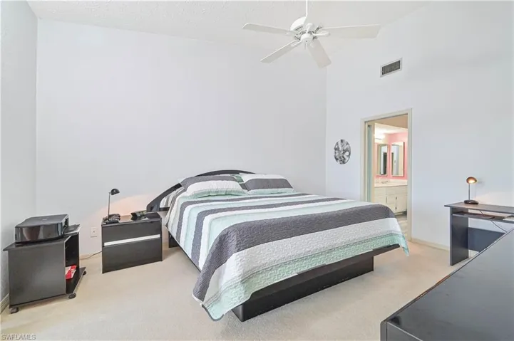 Bedroom with light carpet, ceiling fan, and a high textured ceiling