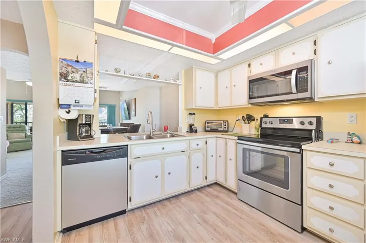 Kitchen featuring stainless steel appliances, light countertops, light wood-style floors, white cabinetry, and a ceiling fan