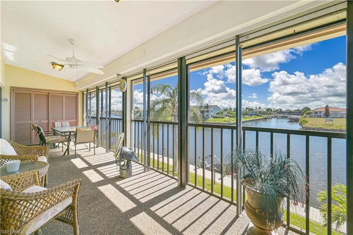 Sunroom / solarium with lofted ceiling, a ceiling fan, a water view, outdoor dining area, and a residential view