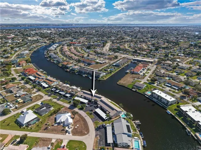 Aerial view of property and surrounding area featuring nearby suburban area and a nearby body of water