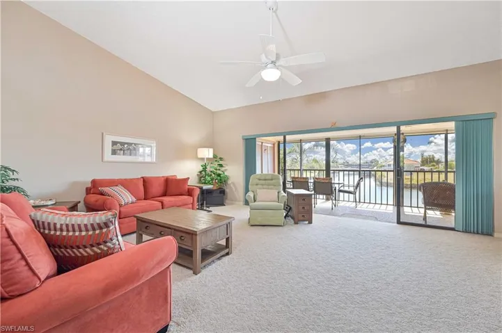 Carpeted living room with a ceiling fan, a water view, and vaulted ceiling