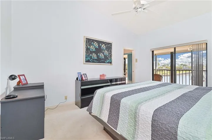 Bedroom with light colored carpet, access to exterior, ceiling fan, lofted ceiling, and a water view
