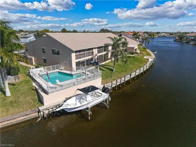 Back of property featuring a water view, a patio, stucco siding, and boat lift