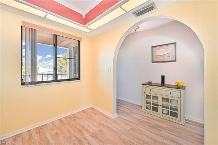 Unfurnished room with arched walkways, light wood-type flooring, and ornamental molding