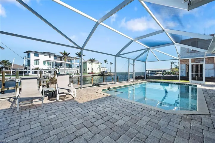View of pool featuring a patio, a water view, and glass enclosure