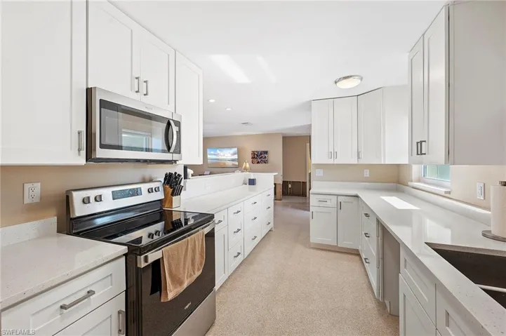 Kitchen featuring white cabinetry, stainless steel appliances, and light stone countertops