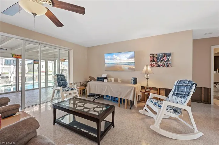 Living room with ceiling fan featuring terrazzo floor and drywall cut
