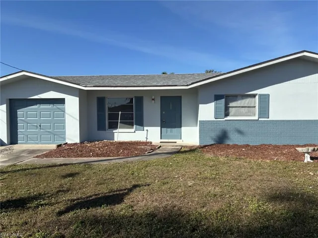 Ranch-style house with brick siding, a front yard, an attached garage, roof with shingles, and driveway
