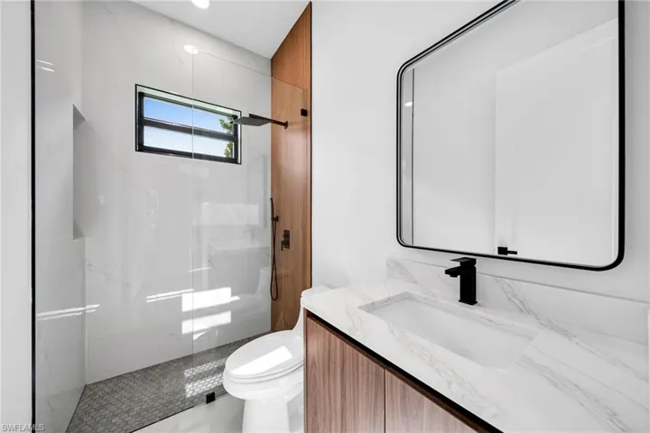 Bathroom featuring toilet, vanity, and a tile shower