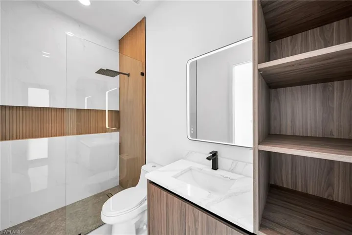 Bathroom featuring vanity, a tile shower, and toilet