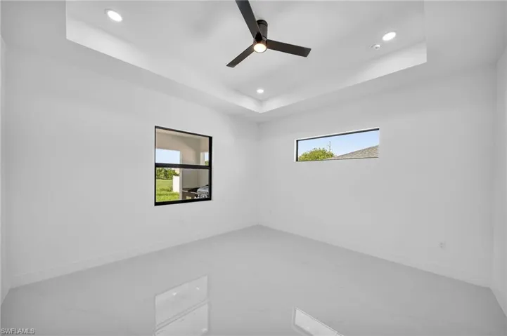 Unfurnished room featuring ceiling fan, tile patterned flooring, and a tray ceiling