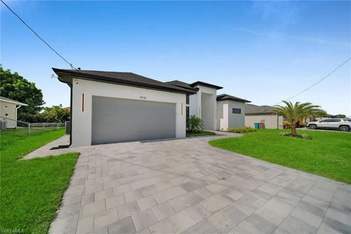View of front facade featuring a garage and a front lawn