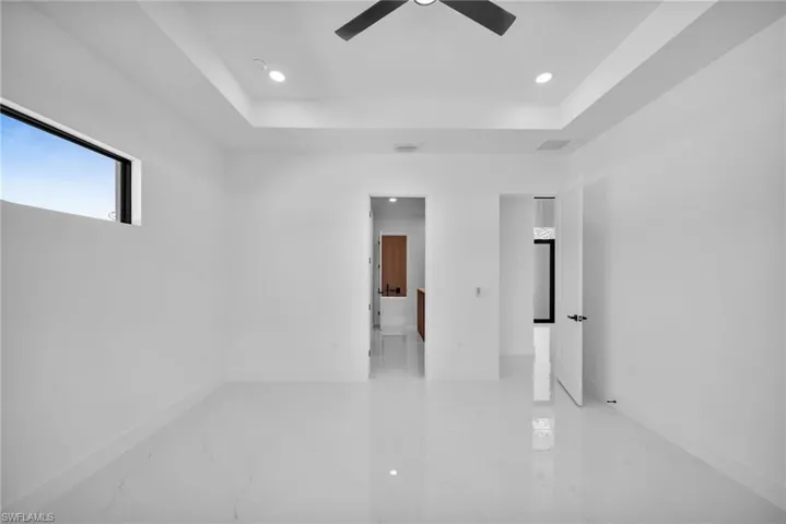 Empty room with ceiling fan, a raised ceiling, and tile patterned floors
