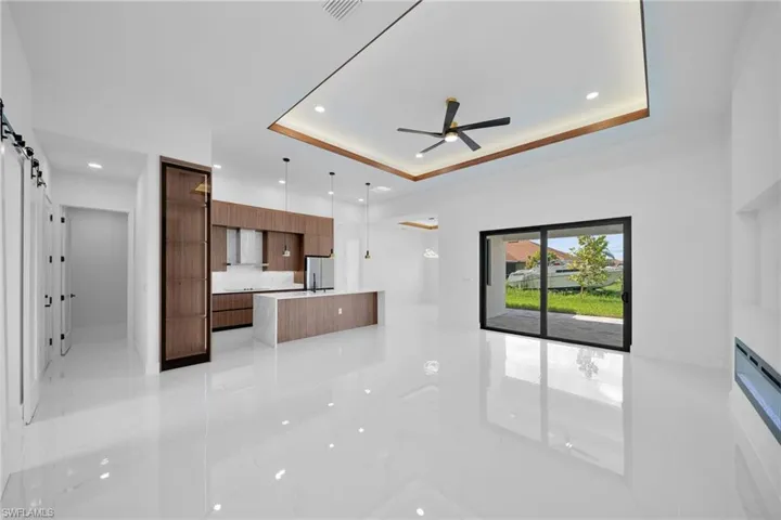 Kitchen featuring refrigerator, ceiling fan, light tile patterned floors, and a tray ceiling